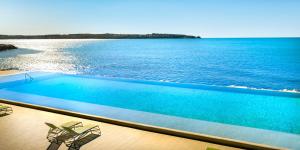 a swimming pool with two chairs and the water at Aminess Maestral Hotel in Novigrad Istria