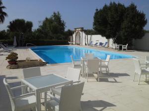 a pool with white tables and chairs next to a pool at Agriturismo Villantica in Tuglie