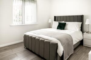 a bedroom with a large bed with white sheets and green pillows at Discovery Suites in Liverpool