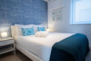 um quarto com uma grande cama branca com toques azuis em Feel Nazaré - Nautical House na Nazaré