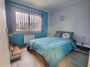a blue bedroom with a bed and a window at Chalet ( Paris , Disneyland ) in Gretz-Armainvilliers