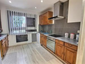 a kitchen with wooden cabinets and a large window at Chalet ( Paris , Disneyland ) in Gretz-Armainvilliers