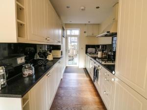 a kitchen with white cabinets and a wooden floor at Blacksmiths Retreat, 50 Holgate Road in York
