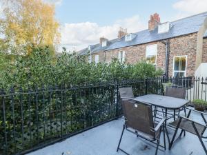 a patio with a table and chairs in front of a fence at Blacksmiths Retreat, 50 Holgate Road in York