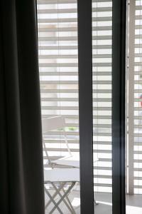 una silla frente a una ventana con persianas en Hotel Benvenuto, en Caorle