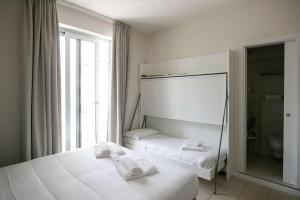 um quarto branco com 2 camas e uma janela em Hotel Benvenuto em Caorle