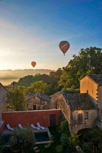 two hot air balloons are flying over a city at La Maison Rouge d'Uzes B&B in Uzès