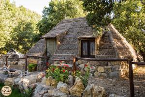 an old stone house with a thatch roof at HAPPY GLAMPING MADONIE in Polizzi Generosa