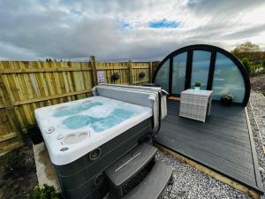 bañera de hidromasaje en la parte superior de una terraza de madera en Highland Premier Glamping Pods en Beauly