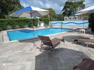a swimming pool with an umbrella and chairs and a table and an umbrella at Village Hospedagens in Natal