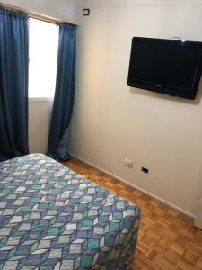 um quarto com uma cama e uma televisão de ecrã plano na parede em Departamento Av. Colon (Ubicacion 9.8 puntos) em Mendoza