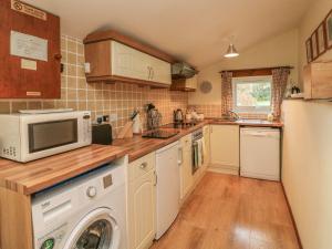 a kitchen with a microwave and a washer and dryer at Beech Cottage in Ilfracombe