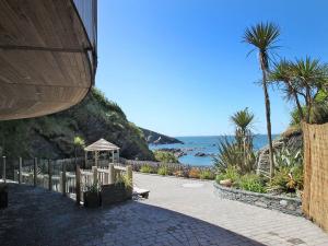a walkway next to the ocean with palm trees at Beech Cottage in Ilfracombe