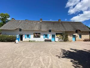una casa con il tetto di paglia su un campo sterrato di Maison avec piscine a Saint-André-des-Eaux