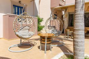two swing chairs and a table on a patio at Ilios Malia Hotel Resort in Malia