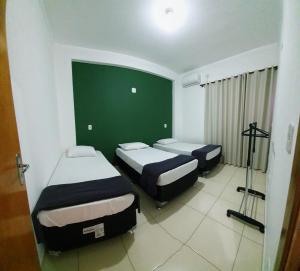 a room with two beds and a green wall at Casa no centro com 4 quartos e ar condicionado in São João Batista do Glória