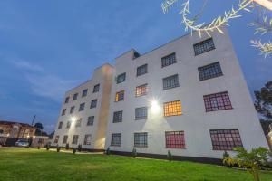 a white building with many windows on a grass field at Fully furnished 1-bedroom Apartment in Eldoret in Eldoret