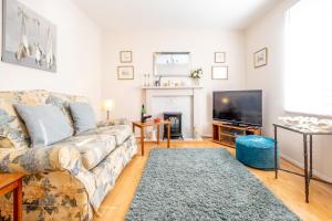 a living room with a couch and a tv at The Britten - Aldeburgh Coastal Cottages in Aldeburgh