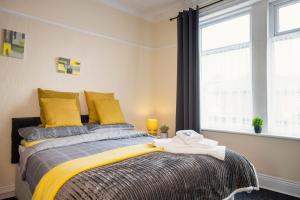 a bedroom with a bed with yellow pillows and a window at Dunes Hotel in Whitley Bay