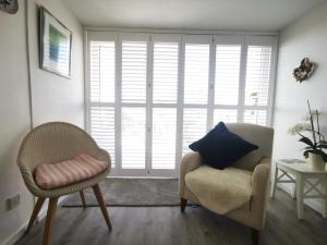 ein Wohnzimmer mit 2 Stühlen und einem Kissen auf einem Stuhl in der Unterkunft Sea View 3 bedroom seaside property in Chichester