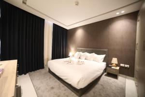 a bedroom with a large bed with white sheets and pillows at فندق صحارى الخليج Sahara Gulf Hotel Apartments in Amman
