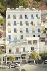 a large white building with cars parked in a parking lot at Glaros Hotel Apartment in Agia Galini