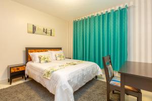 Schlafzimmer mit einem Bett, einem Schreibtisch und einem grünen Vorhang in der Unterkunft Fully furnished 1-bedroom Apartment in Eldoret in Eldoret