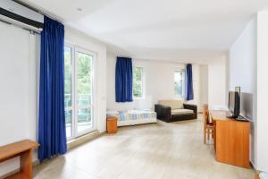 a living room with blue curtains and a bed and a tv at Hotel Park 2 in Kiten