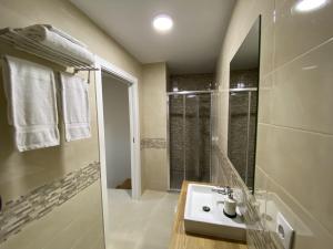 uma casa de banho branca com um lavatório e um chuveiro em Pousadas Mariñeiras,sl - AT "Camiño da Barca" em Muxía