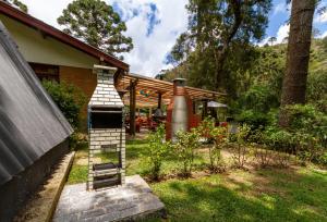 a house with a porch with a bench in the yard at Empório reserva da serra - Opções de chalés e Hidromassagem in Campos do Jordão
