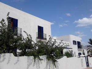 een wit gebouw met blauwe ramen en een hek bij Alsur in Calabardina