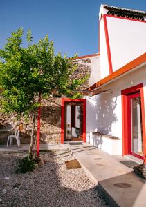 a tree in front of a building with red doors at Casa das Mouriscas in Casalão