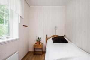 a white bedroom with a bed and a window at Solar Lake Cottage in Jönköping