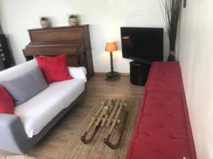 a living room with a white couch and a television at - Le Patio - Calme, Chaleureux, Unique in Besançon