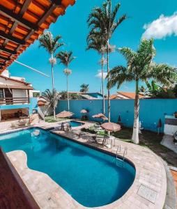 una piscina con palme e una parete blu di GRANADA PARK HOTEL a Rio das Ostras