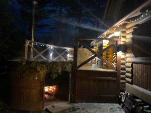 a cabin with lights on the outside at night at Villa "Затишна" in Mykulychyn