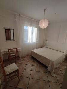 1 dormitorio con 1 cama, 1 silla y 1 ventana en Bougainvillea, en Marina di Modica