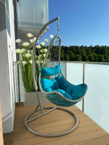 a swing chair on a balcony with blue pillows at Apartament Coral in Grzybowo