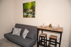 a living room with a couch and a table with stools at DG LOCATION in Saint-Quentin