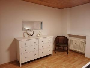 a bedroom with a dresser with a mirror and a chair at Ferienwohnung Elena in Zweibrücken