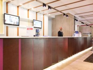 a man standing at a reception counter in an office at Novotel Roma Eur in Rome