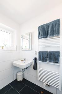 uma casa de banho branca com um lavatório e toalhas azuis em FEWO Fördeblick em Flensburg