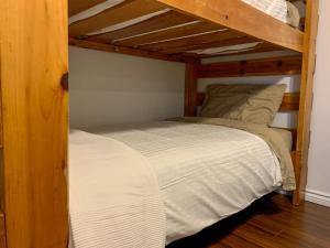 two bunk beds in a room with white sheets at Hiltz House Cellar Suite Near Halifax Ferry in Halifax