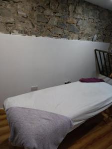 a white bed in a room with a stone wall at Sarahs Cottage at Pheasant Lane in Ráistín +7 photos