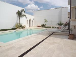 a swimming pool in front of a white building at B&b La Balaustra in Andrano