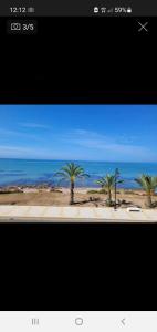 uma imagem de uma praia com palmeiras e o oceano em Apartamento en primera linea de mar. em Múrcia