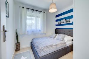 een slaapkamer met een bed met blauwe en witte strepen bij Apartamenty Na Fali - Morski , Błękity , Marynarski in Pobierowo