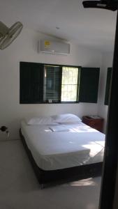 a bedroom with a white bed with two windows at Las Cabanas de Pino Hostel in Santa Fe de Antioquia