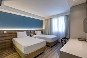 瓜鲁柳斯Comfort Hotel Guarulhos Aeroporto的有两张床和一扇窗户的酒店房间