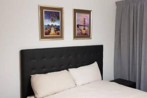 a bedroom with a bed with two pictures on the wall at Crystal lagoon View 3Bed Apartment in Pretoria